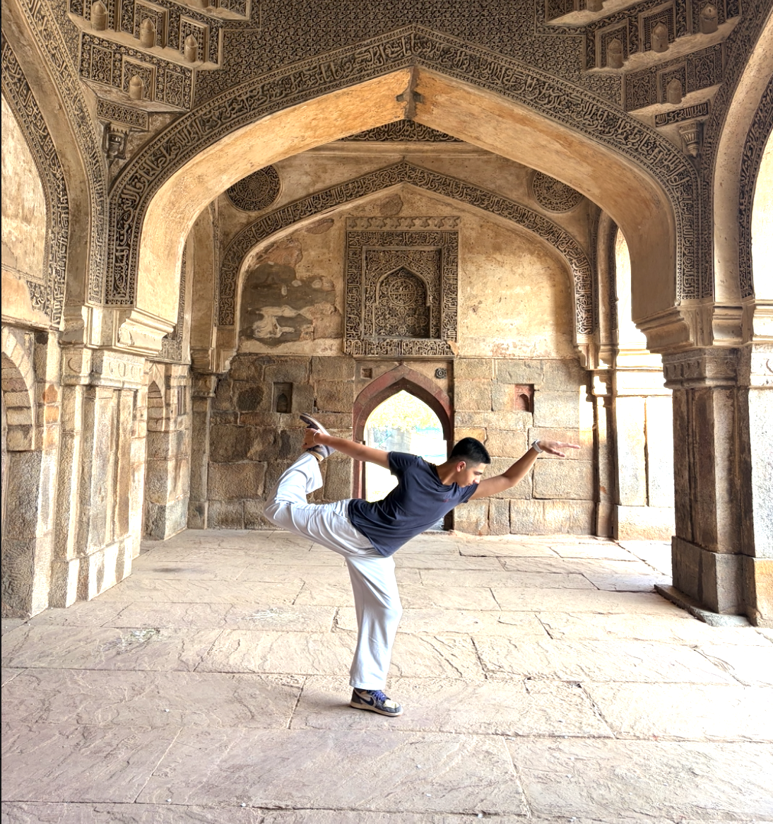 Arnav Ajana holding a dance pose beneath carved stone arches